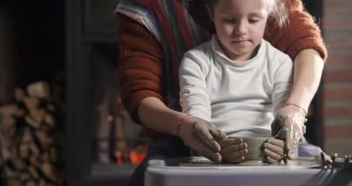 Child Learns Pottery with Adult at Pottery Wheel