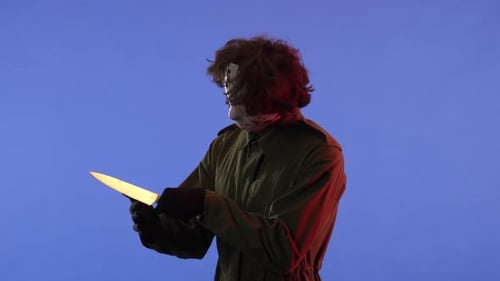 Man in White Mask with Big Sharp Knife on Blue Background with Red Neon Light Image of Jason