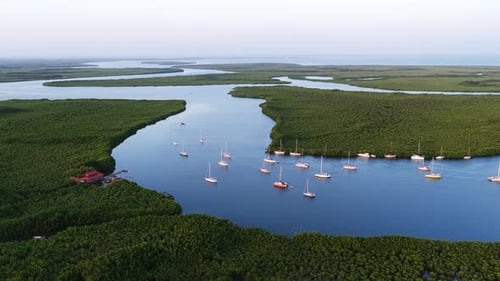 Aerial view of mangrove-lined waterways near Banjul, with anchored sailboats resting on calm blue