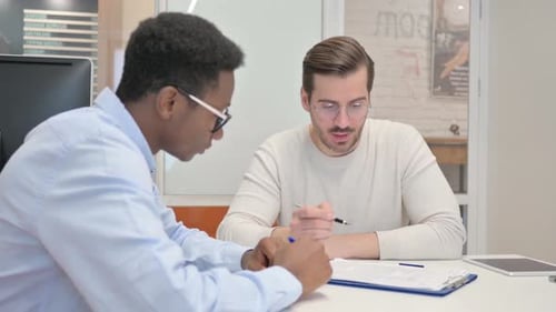 Young Mixed Race People Doing Paperwork in Office
