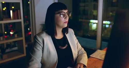 4k video footage of a young businesswoman using a computer at her desk during a late night at work