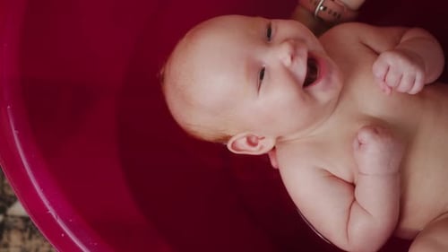 Mother Bathes Her Baby in Pink Bathtub Top View