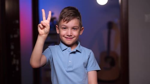 Boy Smiling and Holding Up Peace Sign