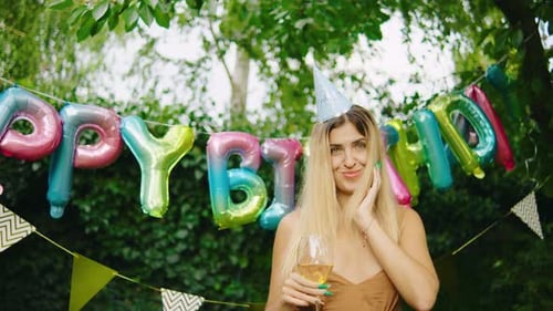 Smiling Woman Celebrates Birthday with Balloons and Wine