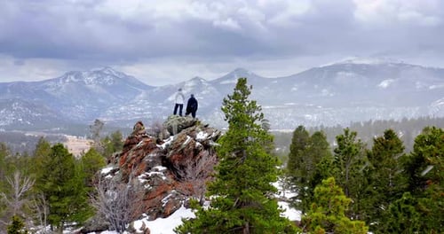 Couple Climbing Rock Formation In Snowy Forest Park, Mountains