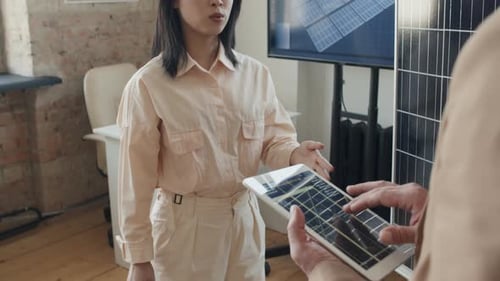 Une ingénieure asiatique discute d'un prototype de batterie solaire avec un collègue de sexe masculin