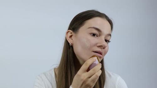 Woman Applying Foundation with Brush in Studio