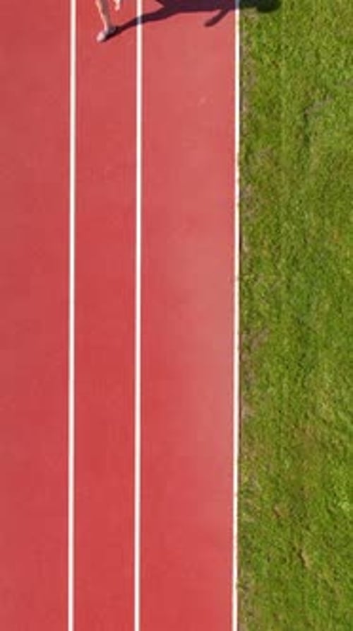 Top View Of Young Woman Running On Red Athletic Track At Stadium