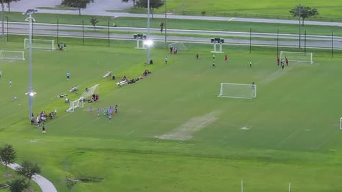 Aerial View of Public Sports Park with Children Engaged in Football Game on Grass Stadium at Sunset