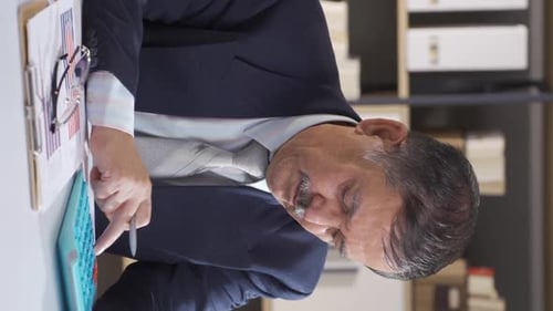 Vertical video of Businessman making calculations.