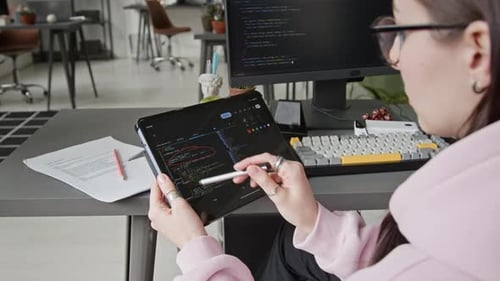Young Woman Reviewing Computer Code on Tablet in Modern Office