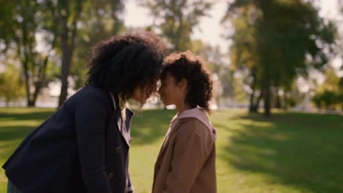 Woman and Girl Holding Hands in Sunny Park