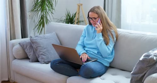 Woman on Couch Using Laptop and Talking on Phone