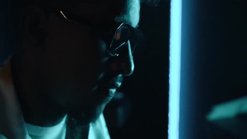 Audio engineer or producer working in a music recording studio with blue LED light playing the piano