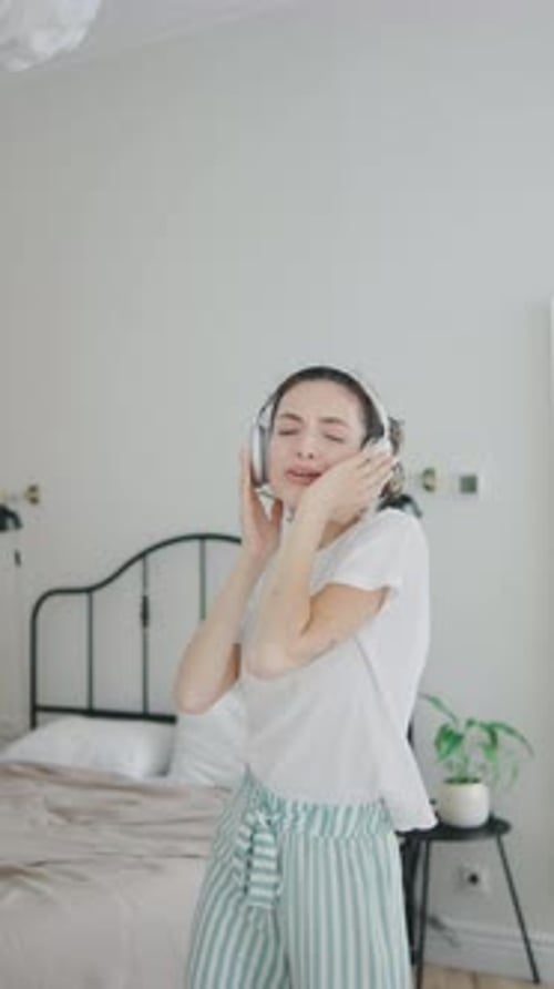Woman with Headphones Dancing Joyfully in Bedroom