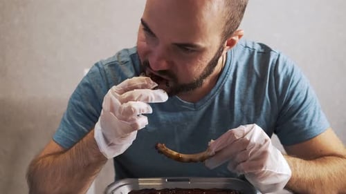 Guy mange de délicieuses côtes de porc cuites avec de la sauce