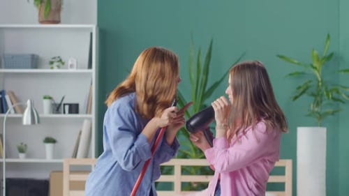 Cheerful Funny Girls Students Dance Sing with a Hairdryer on the Bed