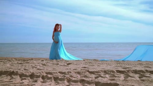Mulher grávida de vestido azul posando na praia. Sessão de fotos românticas. Grávida