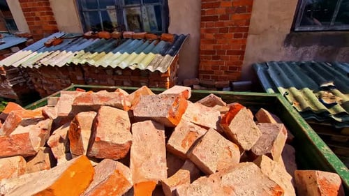 Pile Of Old Red Bricks In Container Under Sunlight With Stacked Bricks Covered With Roof In