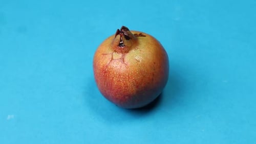 A ripe red pomegranate on a blue background.