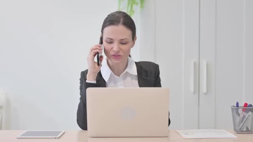Woman In Office Talking On Phone While Working