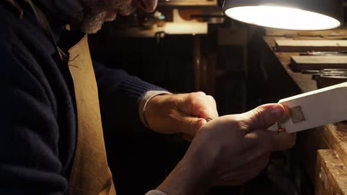 Luthier carving a violin scroll by hand under warm workshop light with precise craftsmanship