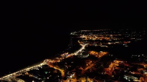Stunning 4K drone footage of the sea at night, with illuminated coastline and city lights