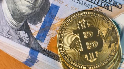 Gros plan d'une pièce de monnaie cryptographique Bitcoin brillante en métal sur des billets en dollars américains