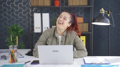 Happy Woman Laughing at her Desk in an Office