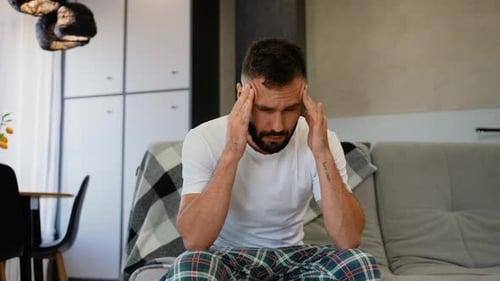 Man with Headache Sitting on a Sofa