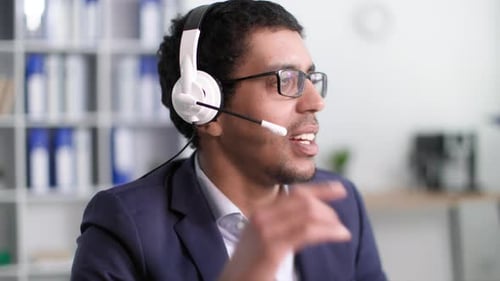 Der junge schwarze Mann arbeitet im technischen Support und kommuniziert mit dem Kunden über ein eingeschaltetes Mikrofon