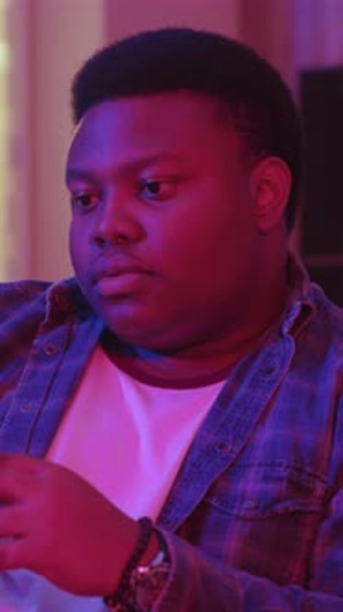 Close Up Serious Young African American Man Typing Message and Looking at Smartphone Screen Sitting