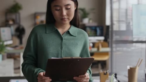 Portrait of Asian Businesswoman Holding Document Folder in Office