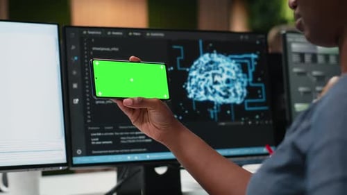 Teléfono con pantalla verde utilizado por una mujer en el lugar de trabajo de una empresa de tecnología