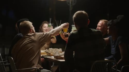 Friends Toasting Drinks Together at Night Outdoors