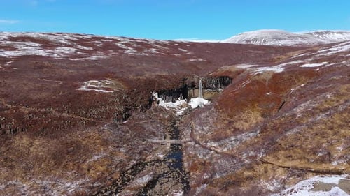 Blue skyline snowy mountain Waterfalls in Icelandic volcanic terrain aerial fly