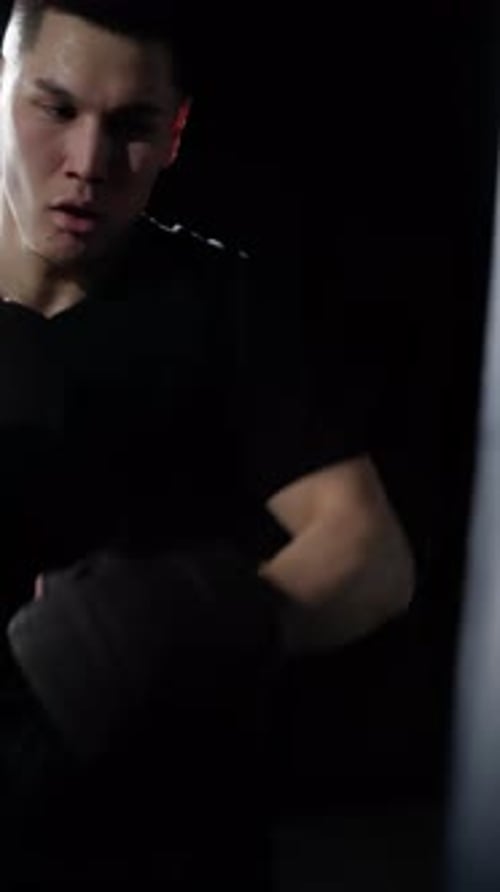 Schläge eines Boxers in einem schwarzen T-Shirt und dunklen Boxhandschuhen