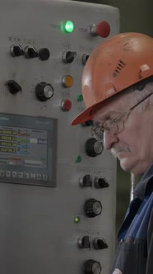 Man Operates Factory Machine Control Panel