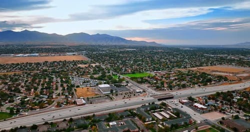 Sunset scenery of green low-rise urban landscape. Cars run quickly by the highways.