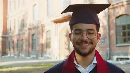 Cheerful Holder of Masters Degree in Hat and Gown Looking at Camera