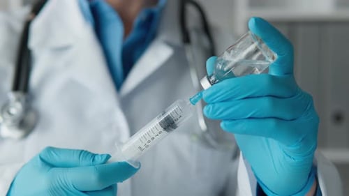 Medical Professional Fills Syringe with Liquid from Vial