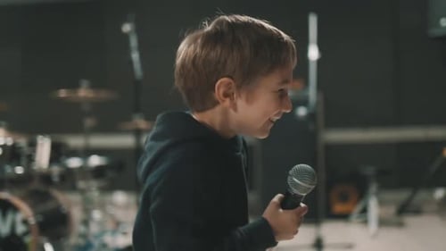 Smiling Boy Holding Microphone in Recording Studio