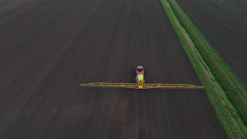 Tractor Spraying Pesticides On agricultural field With Sprayer