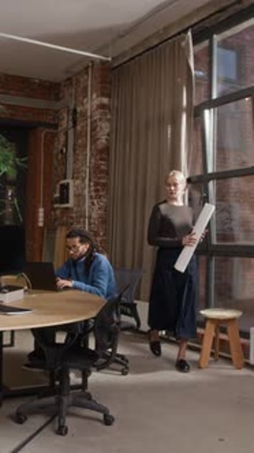 Vertical of Female Architect Unfolding Printed Floor Plan on Office Table