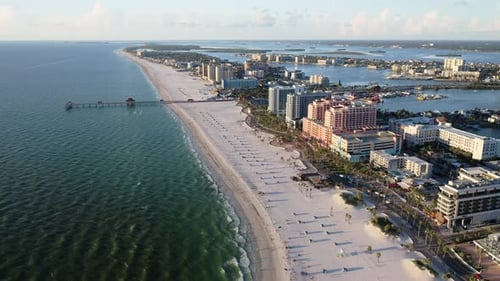 Wide sandy shoreline with ocean pier and beachfront hotels — aerial perspective