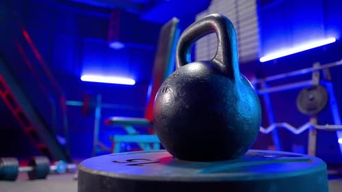 Black Round Kettlebell on a Blurred Background of an Empty Gym