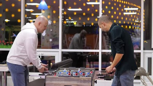 Two Happy and Joyful Friends Together Playing Table Football in the Playing Center
