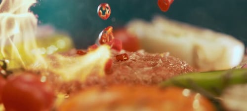 Red spices falling on hamburger