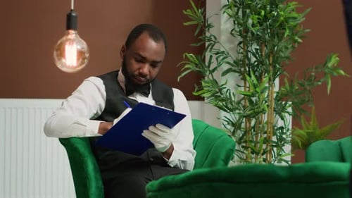 Dapper Man with Beard Writes on Clipboard