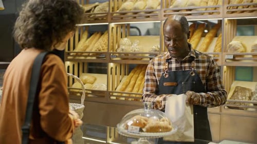 Black Baker Selling Fresh Croissants to Customer in Bakery Shop